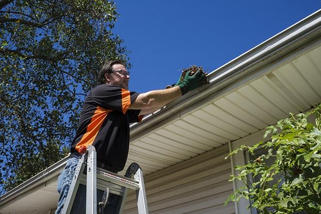 a skilled worker fixing broken gutter on a roof in Boston, MA